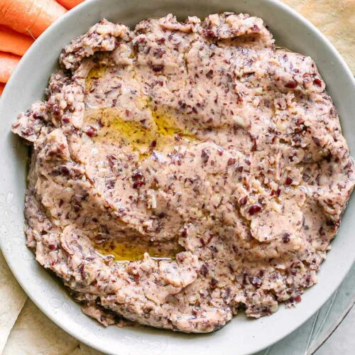 a bowl of kidney bean hummus on a plate with pita bread for dipping
