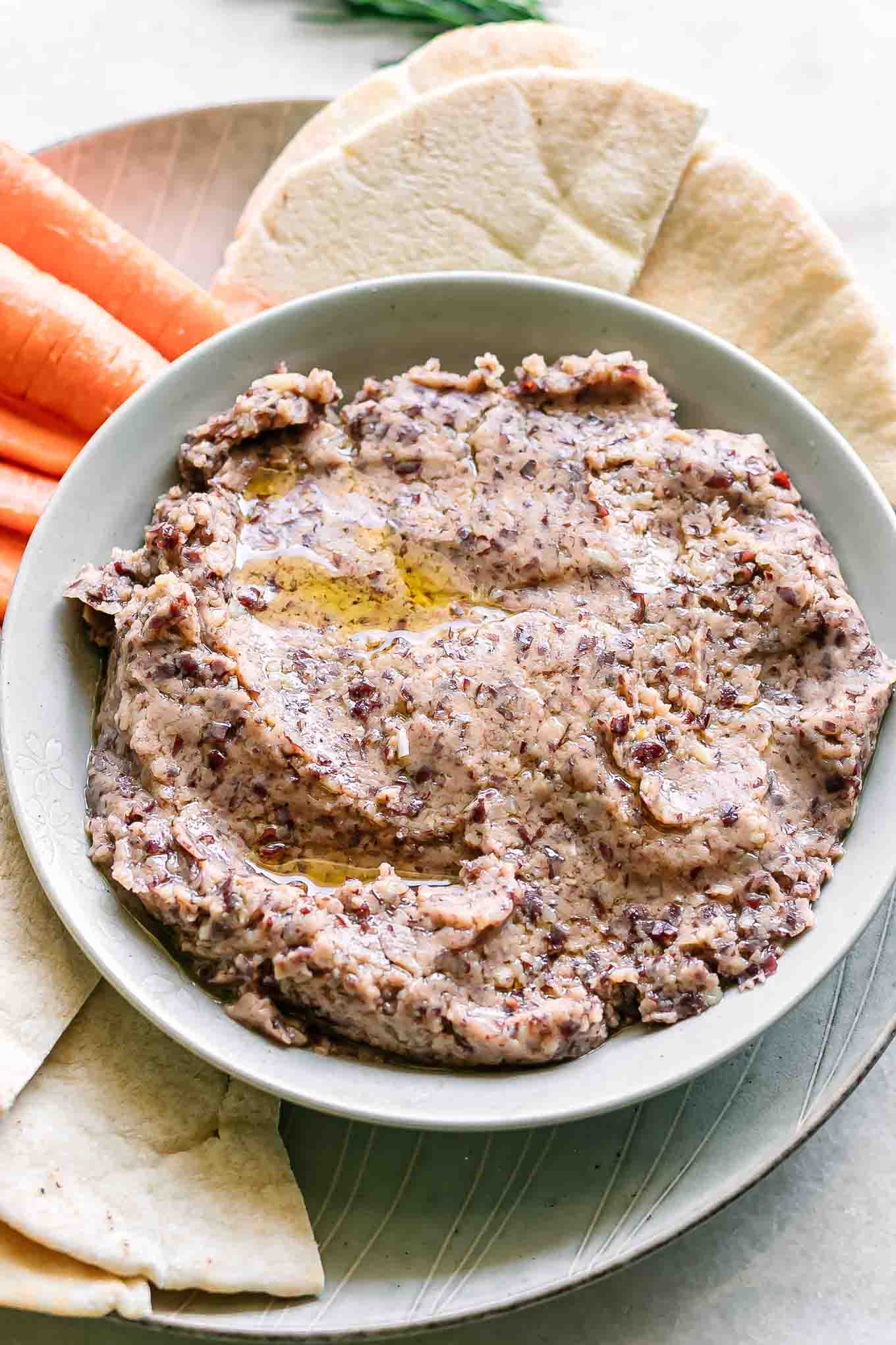 an appetizer plate with a bowl of hummus made of kidney beans with bread and vegetables for dipping