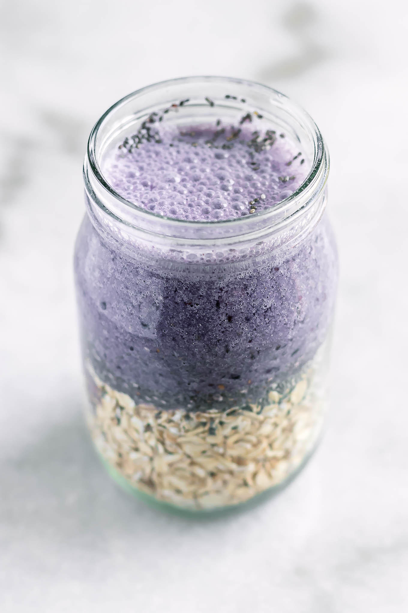 rolled oats and blackberry-flavored milk inside a mason jar on a white table