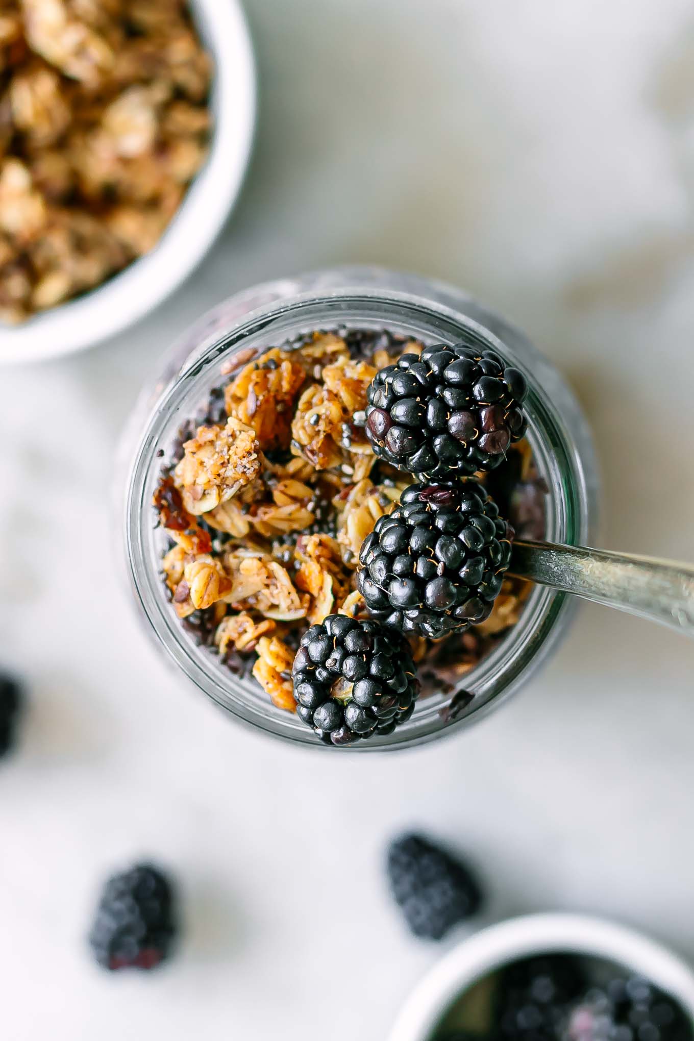 a close up photo of overnight oats garnished with granola and blackberries