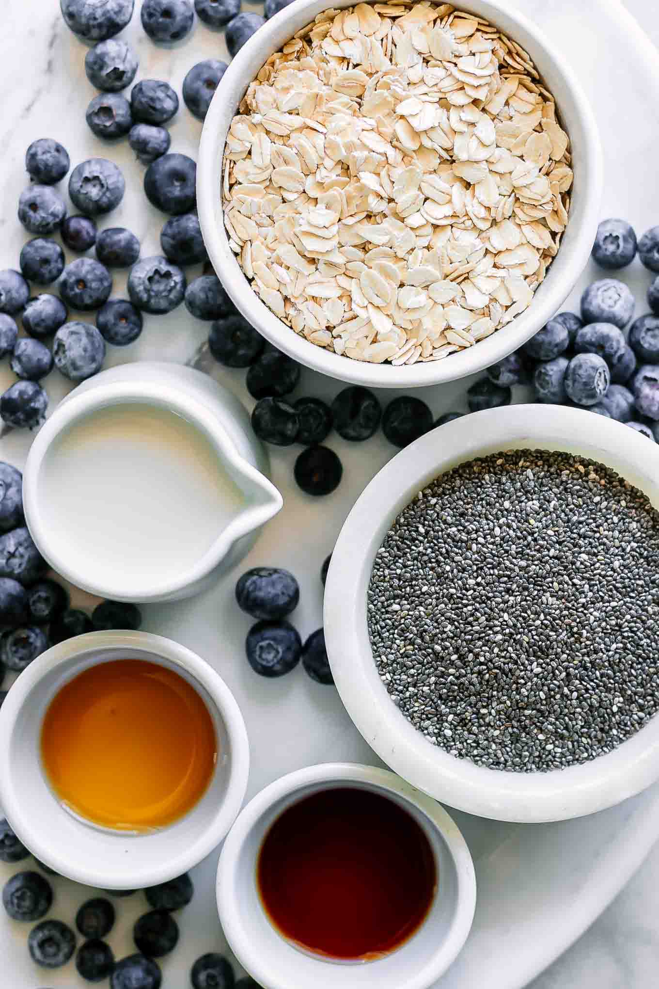 bowls of rolled oats, chia seeds, blueberries, milk, maple syrup, and vanilla for overnight oats