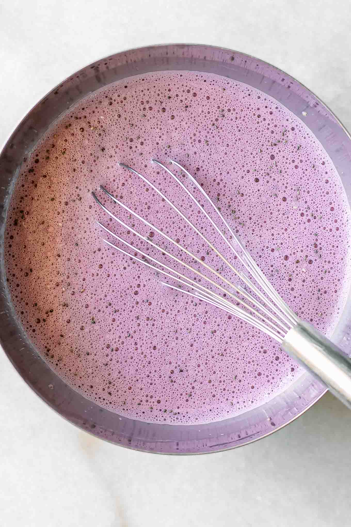 a bowl of milk with blended cherries and chia seeds on a white table