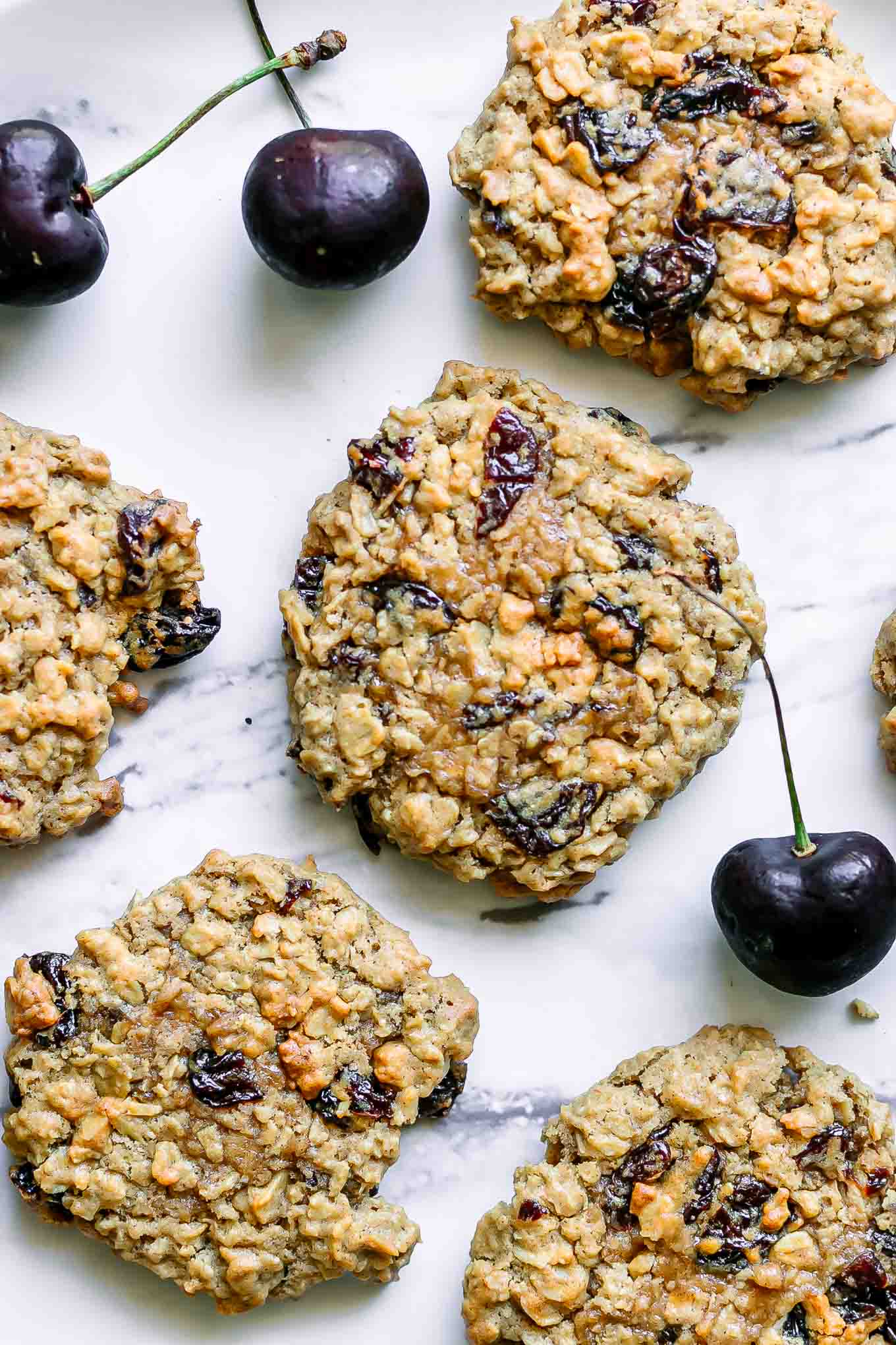 vegan oatmeal cookies with cherries on a white table with fresh cherries