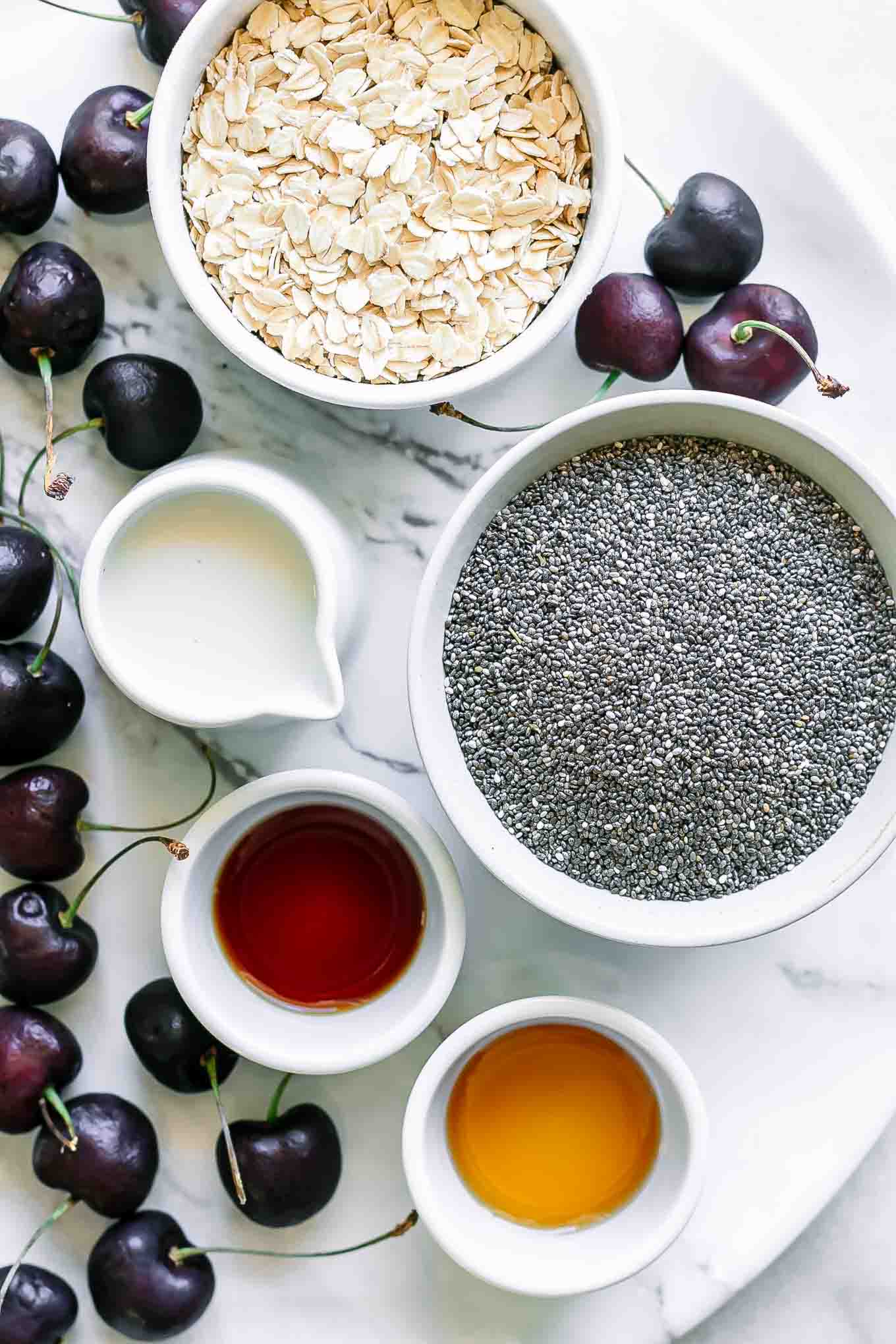 bowls of oats, chia seeds, cherries, milk, vanilla, and maple syrup for overnight oats