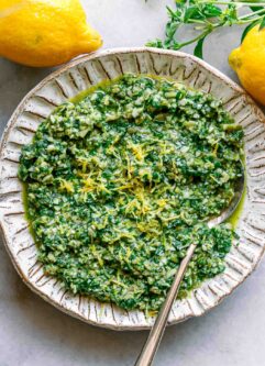 lemon basil pesto on a white plate with lemon zest as garnish