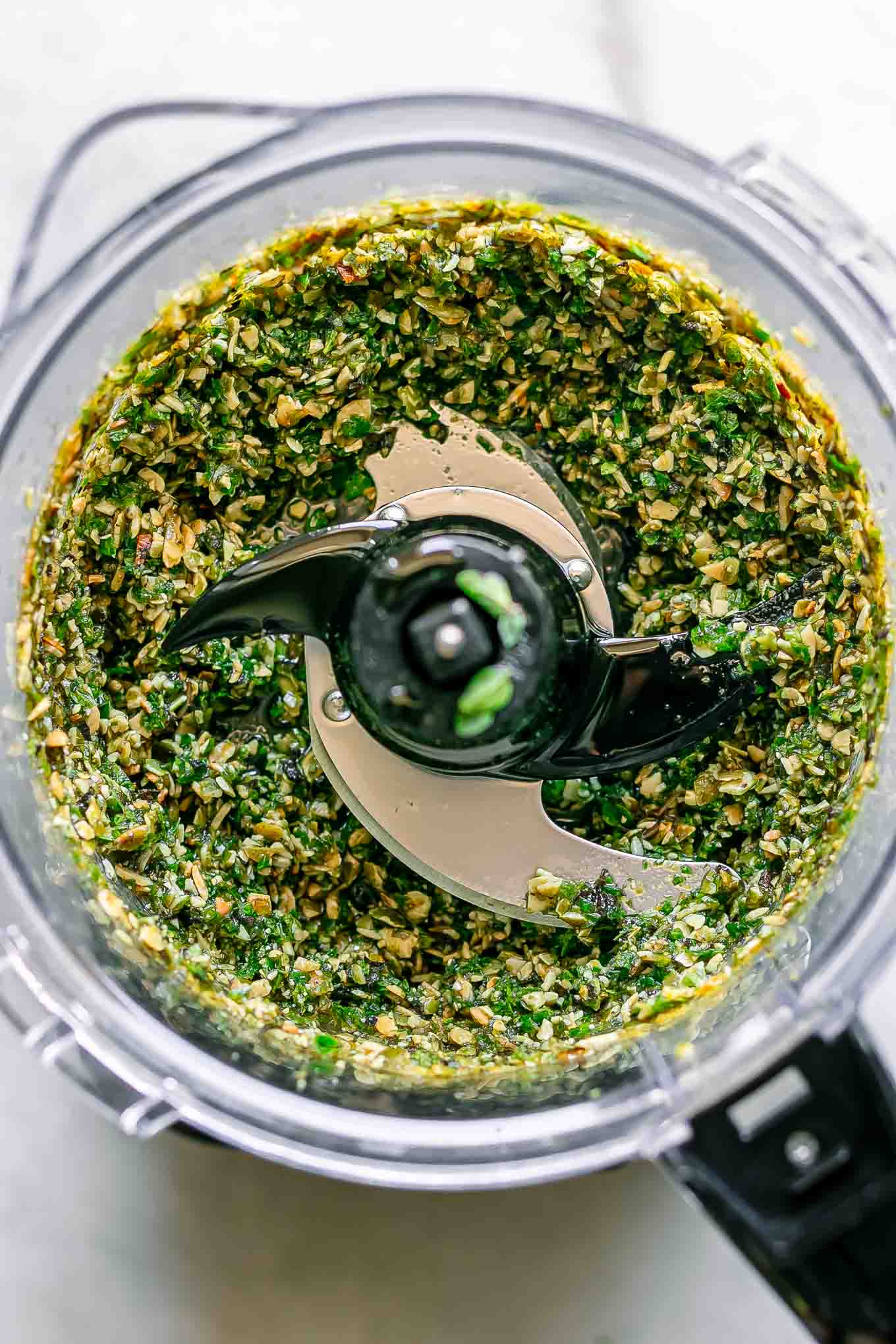 blended oregano pesto inside a food processor on a white table