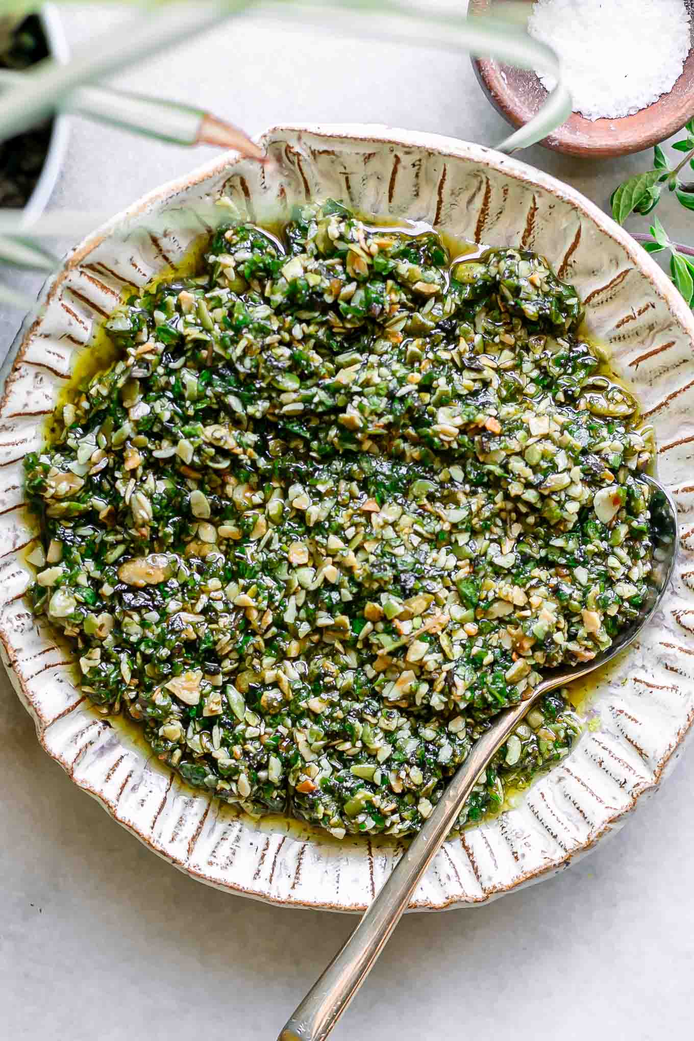 oregano pesto sauce on a white plate with a gold fork