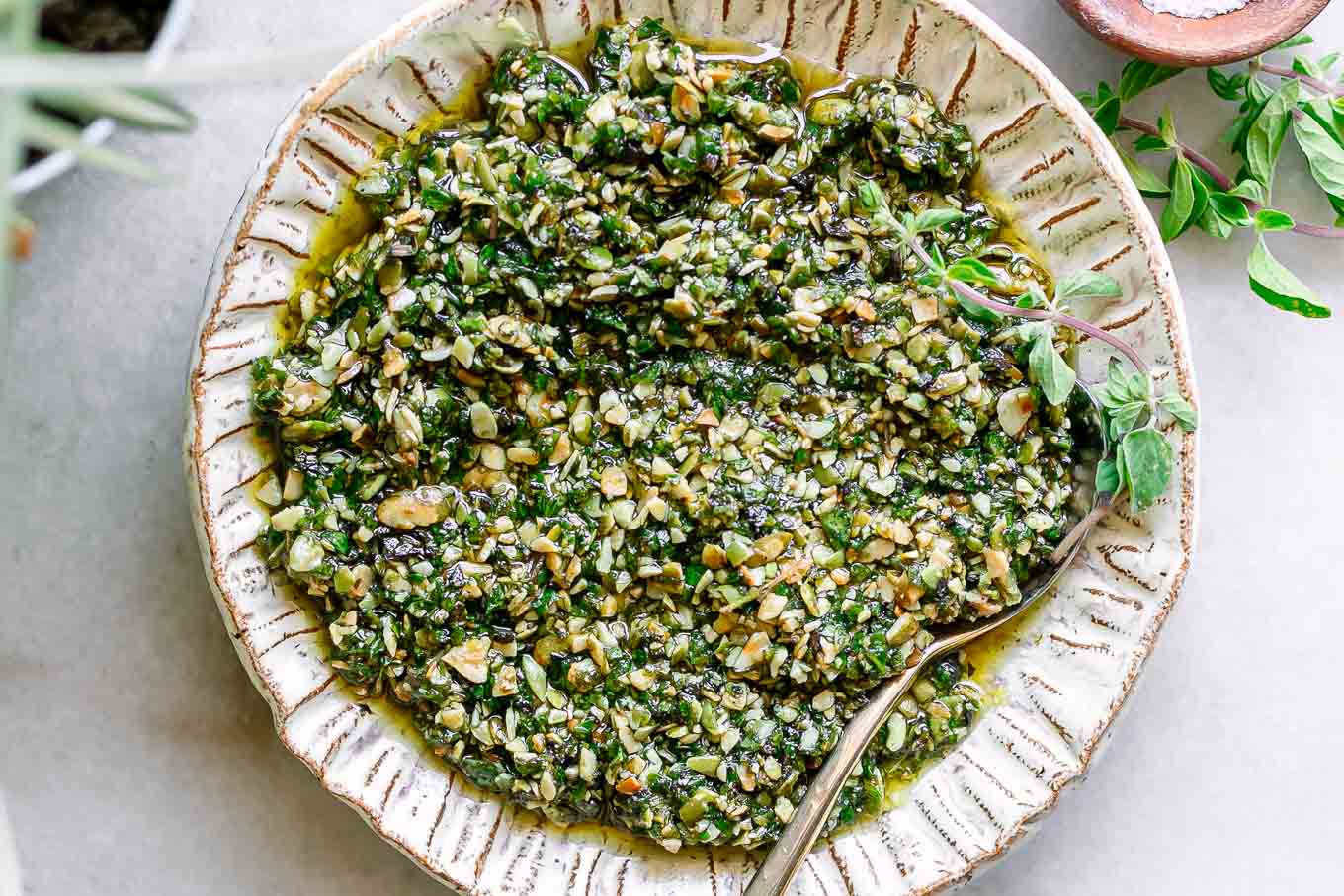 green pesto with oregano leaves on a white plate on a white table