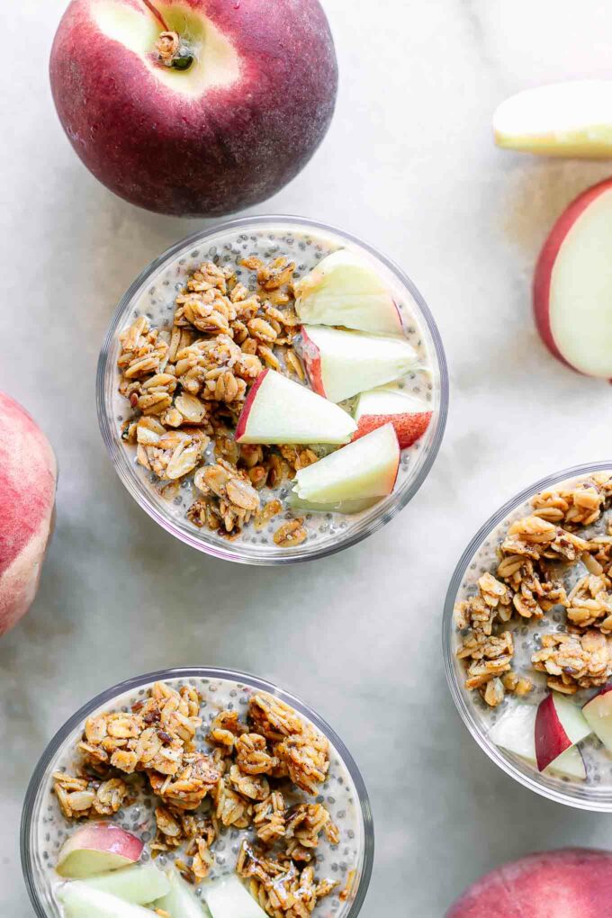 chia pudding with peaches and granola on a white table with fresh peaches