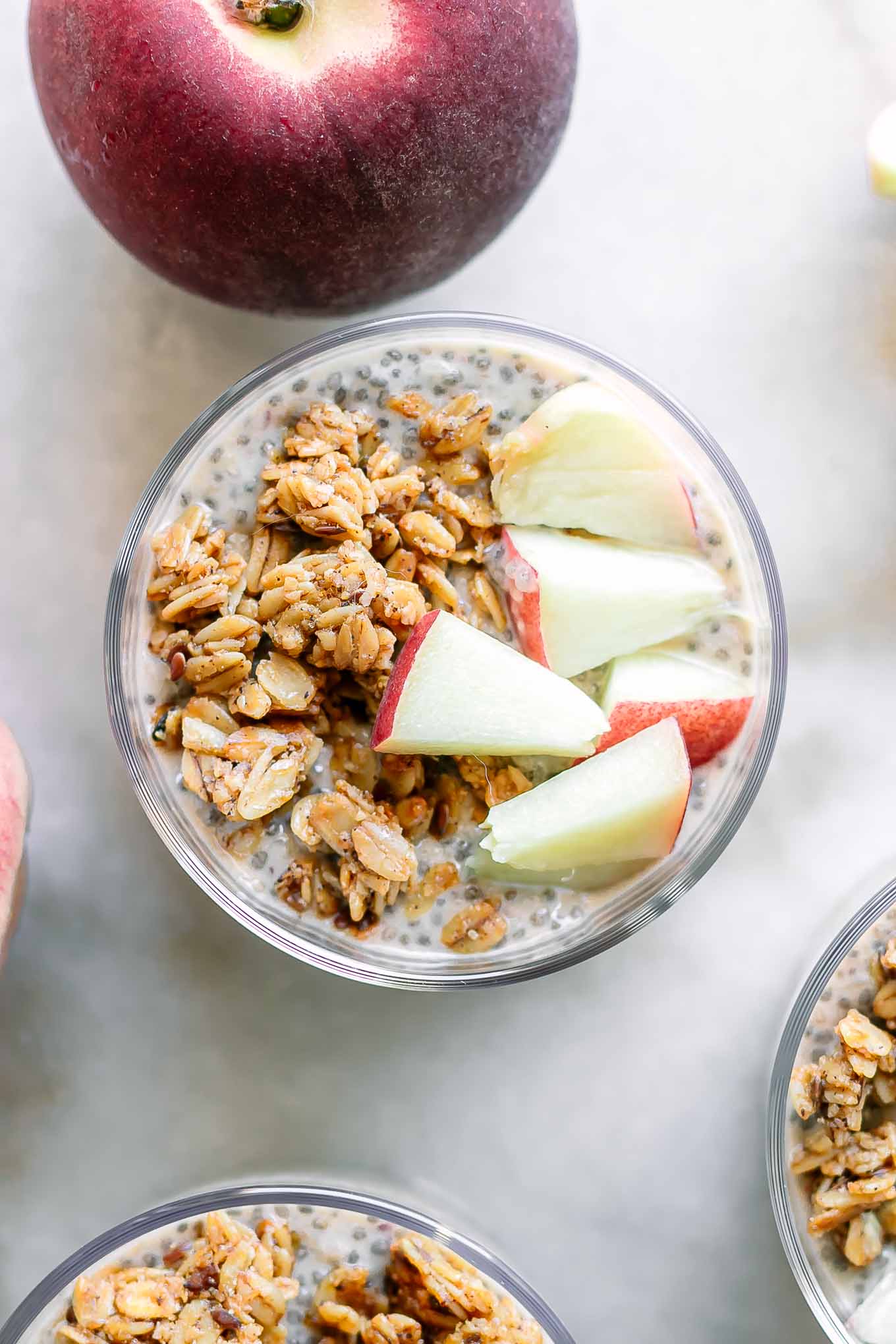 bowls of peach chia pudding with sliced peaches and granola garnish on a white table