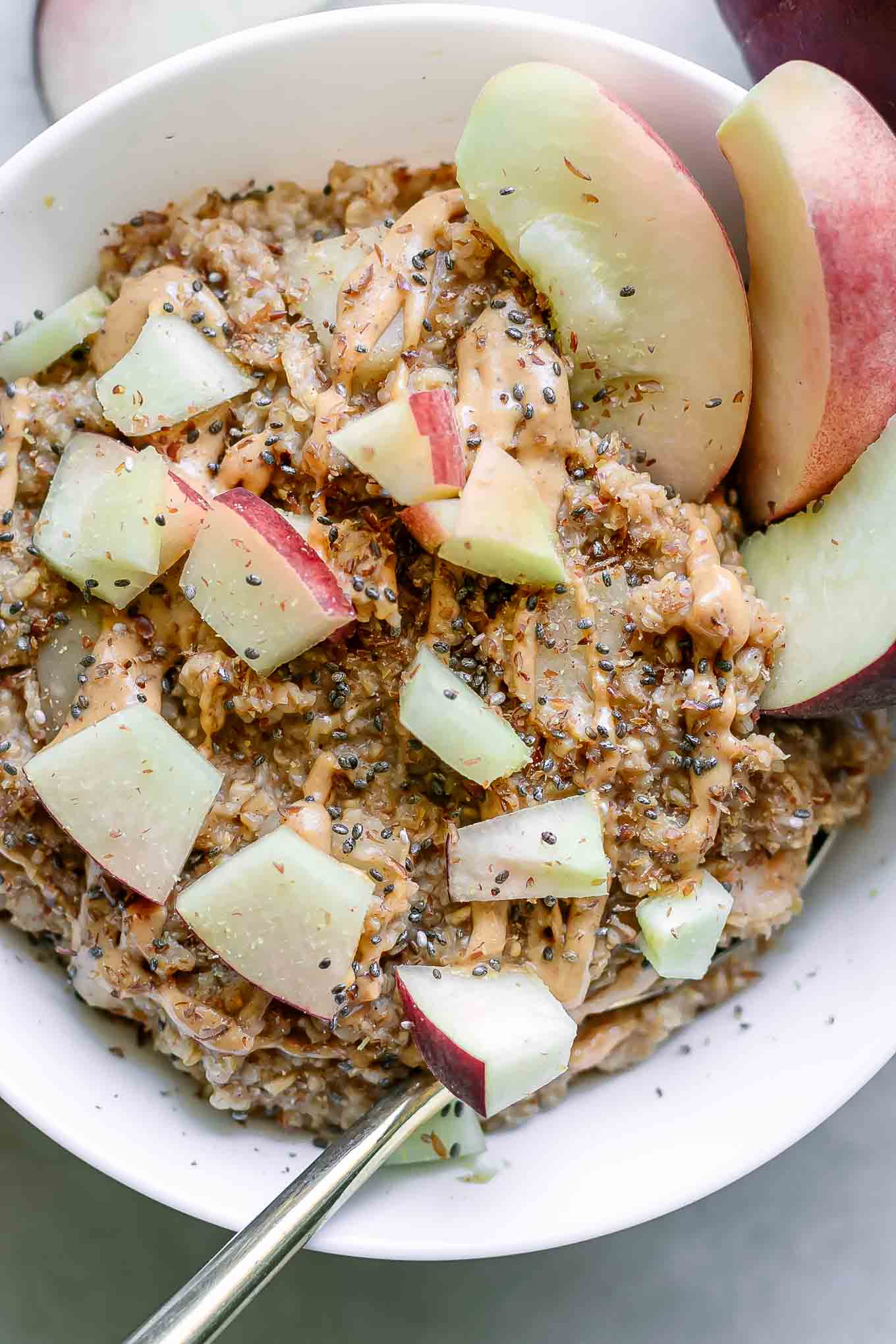 a close up photo of an oatmeal bowl with chopped peaches on a white bowl