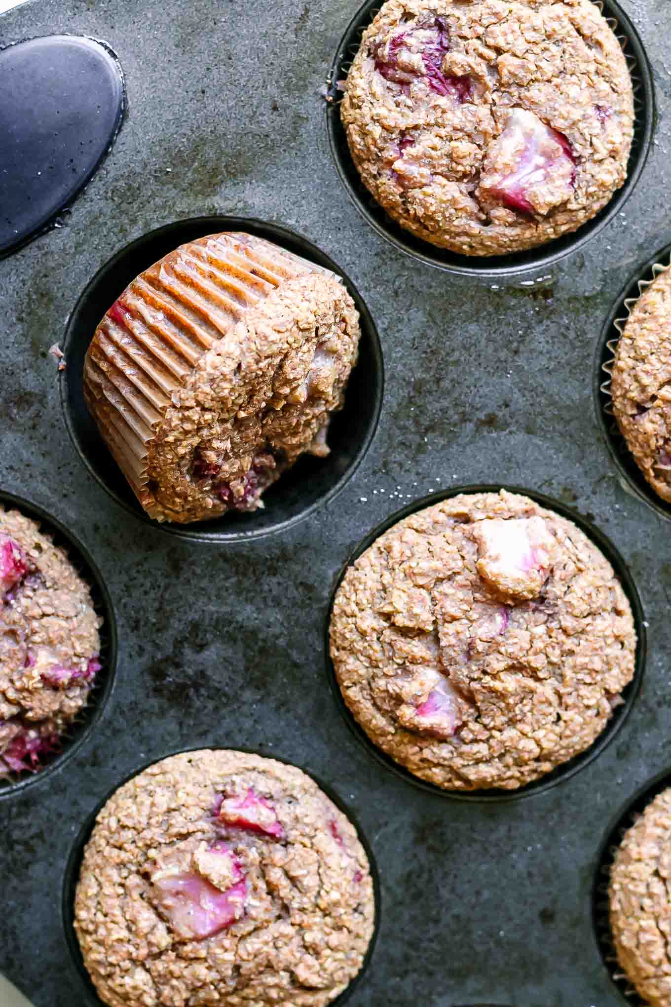 bran muffins with strawberries inside a muffin tin after baking