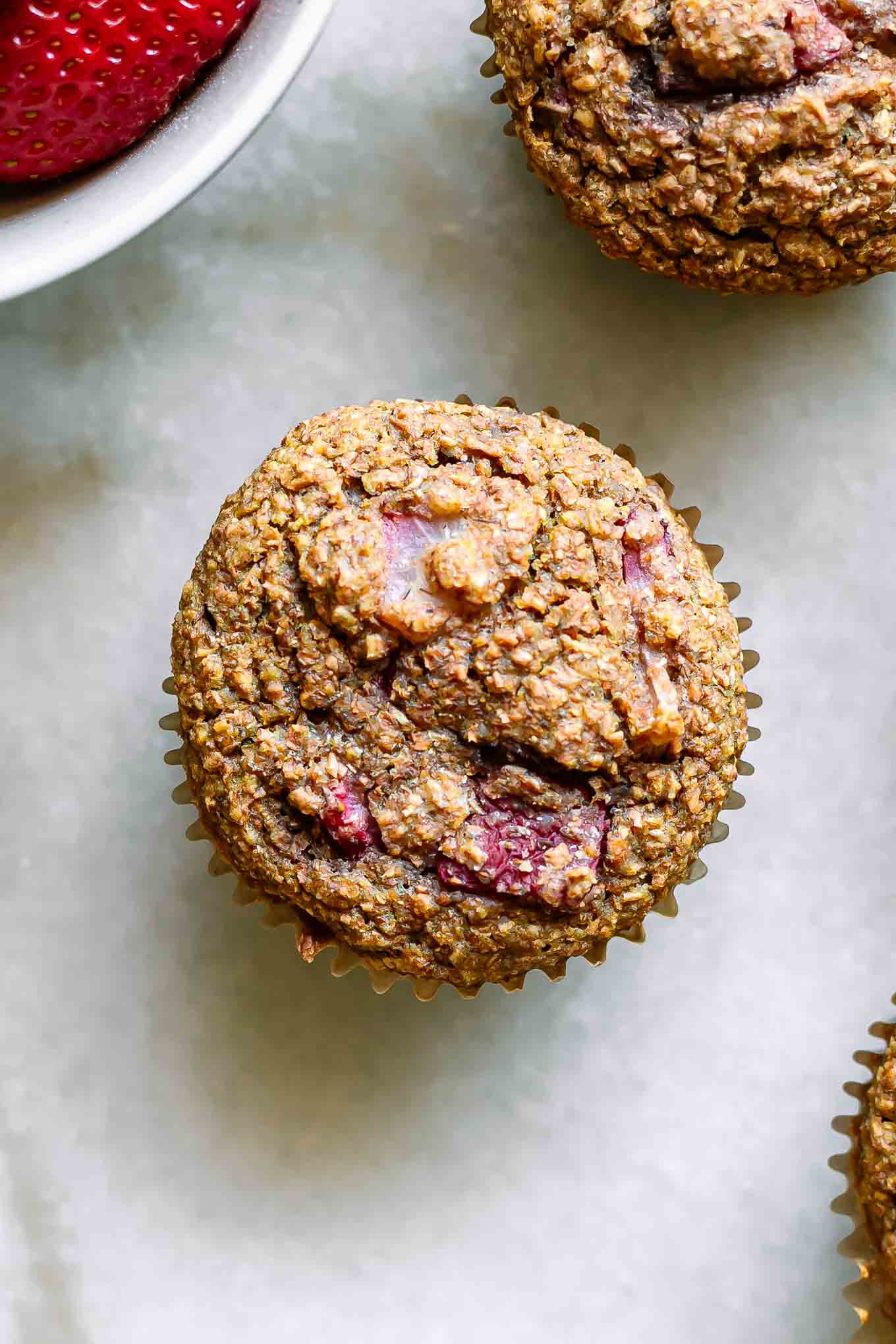 a close up photo of a strawberry bran muffin on a white table