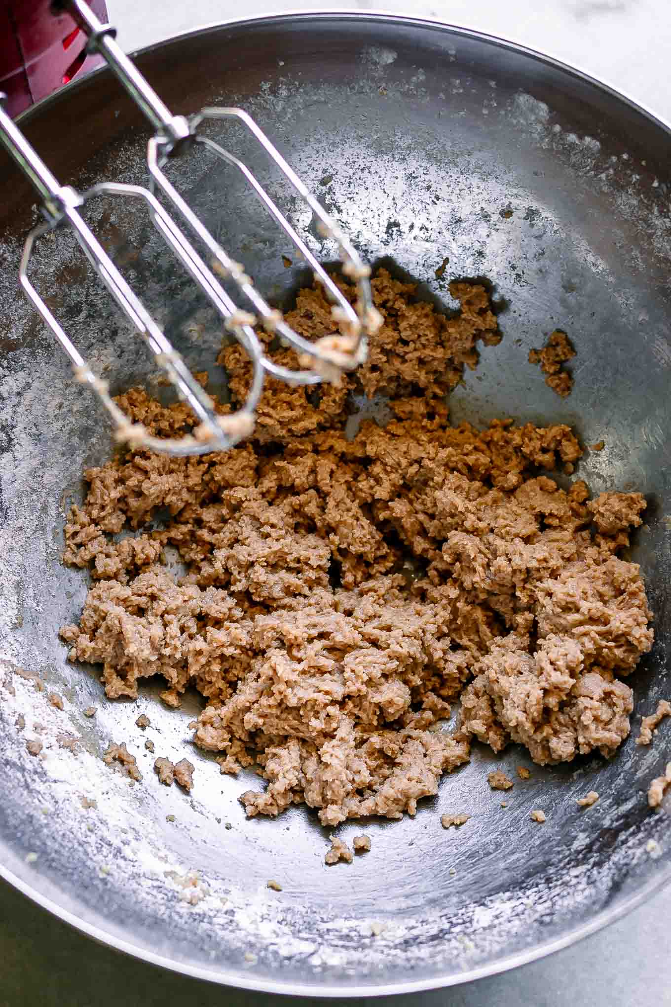 oatmeal cookie dough mix inside a bowl on a table with a kitchen mixer