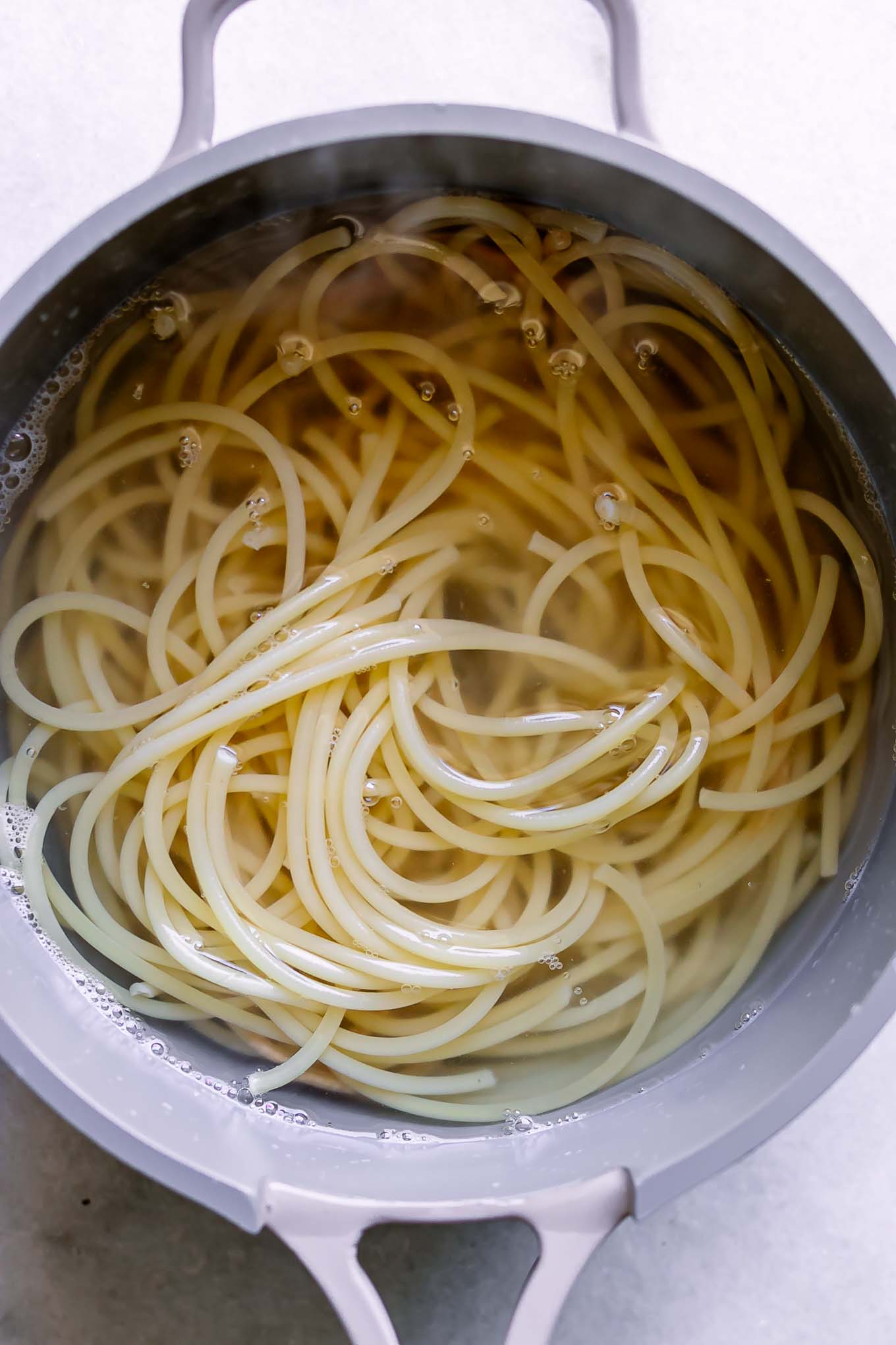 a pot of boiling water with pasta inside on a white table