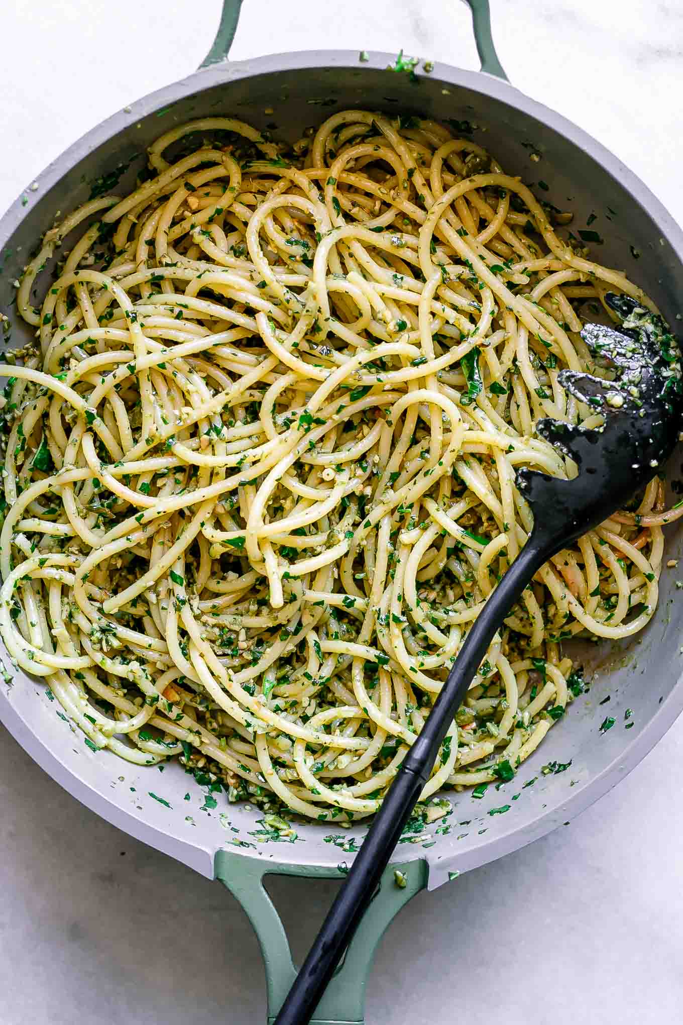 a pan with lemon pesto pasta and a black spoon