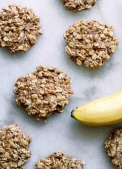 banana oatmeal cookies on a white table with a yellow banana