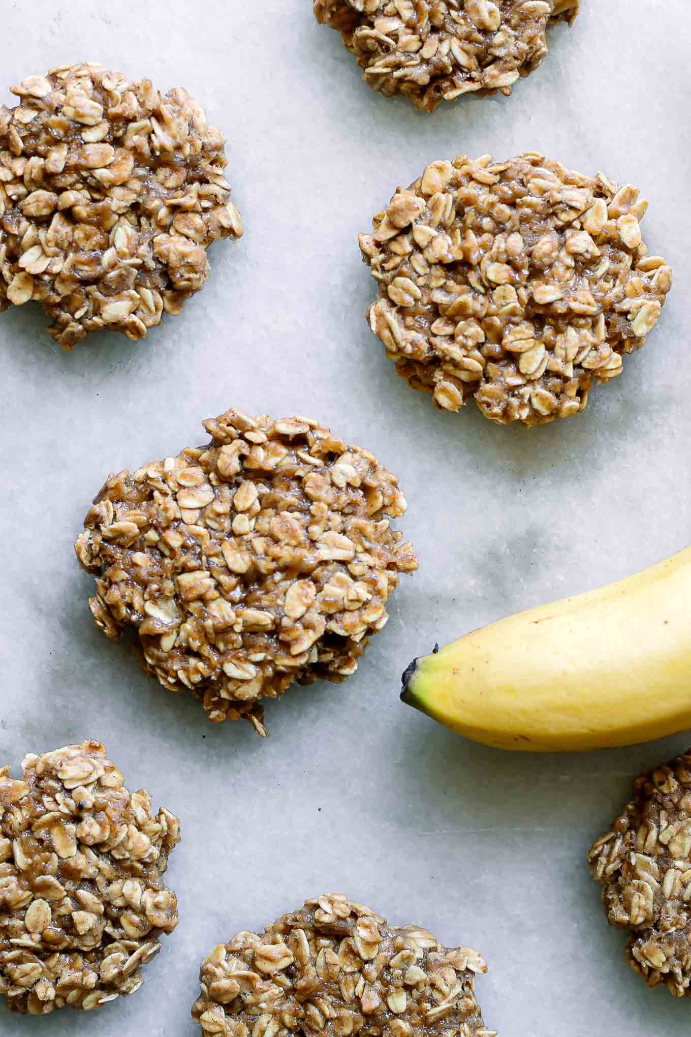 banana oatmeal cookies on a white table with a yellow banana