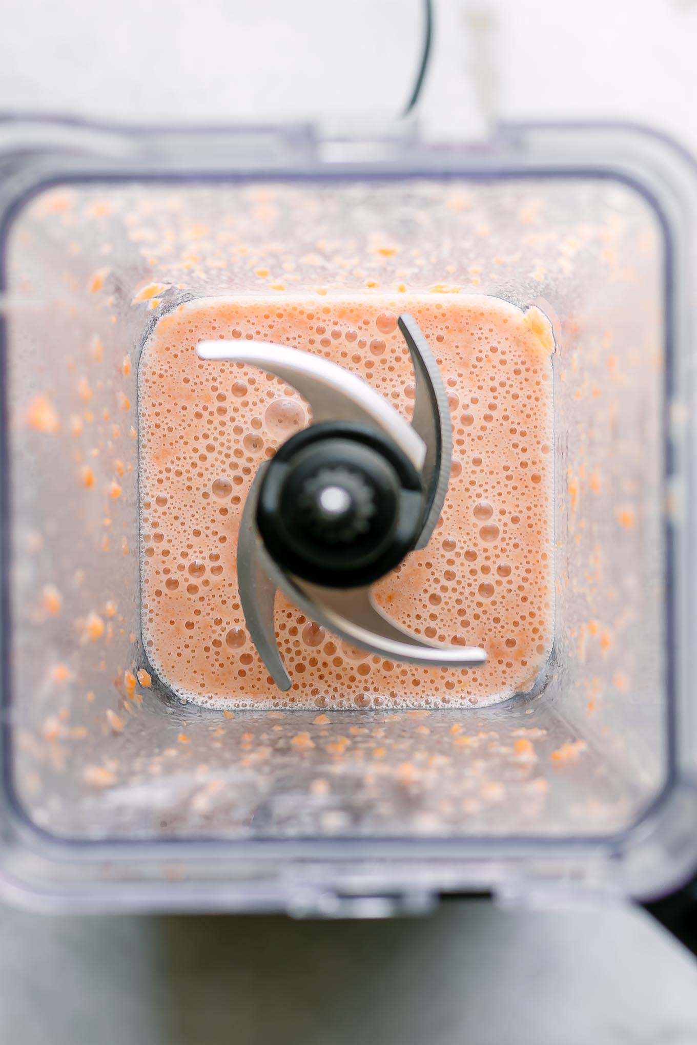 blended apricots with plant-based milk inside a blender on a white table