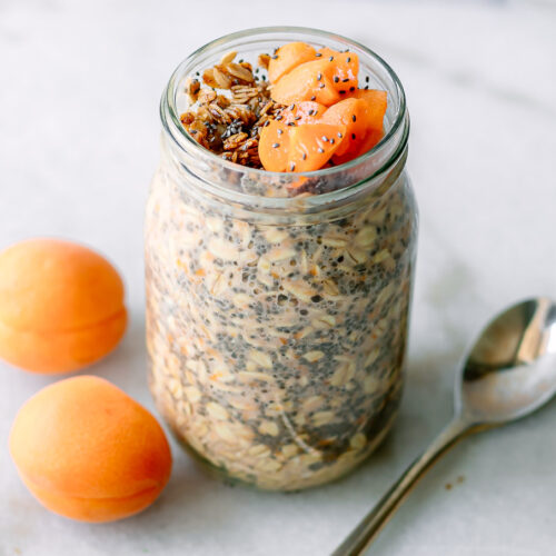 apricot flavored overnight oats garnished with granola and cut apricots on a white table