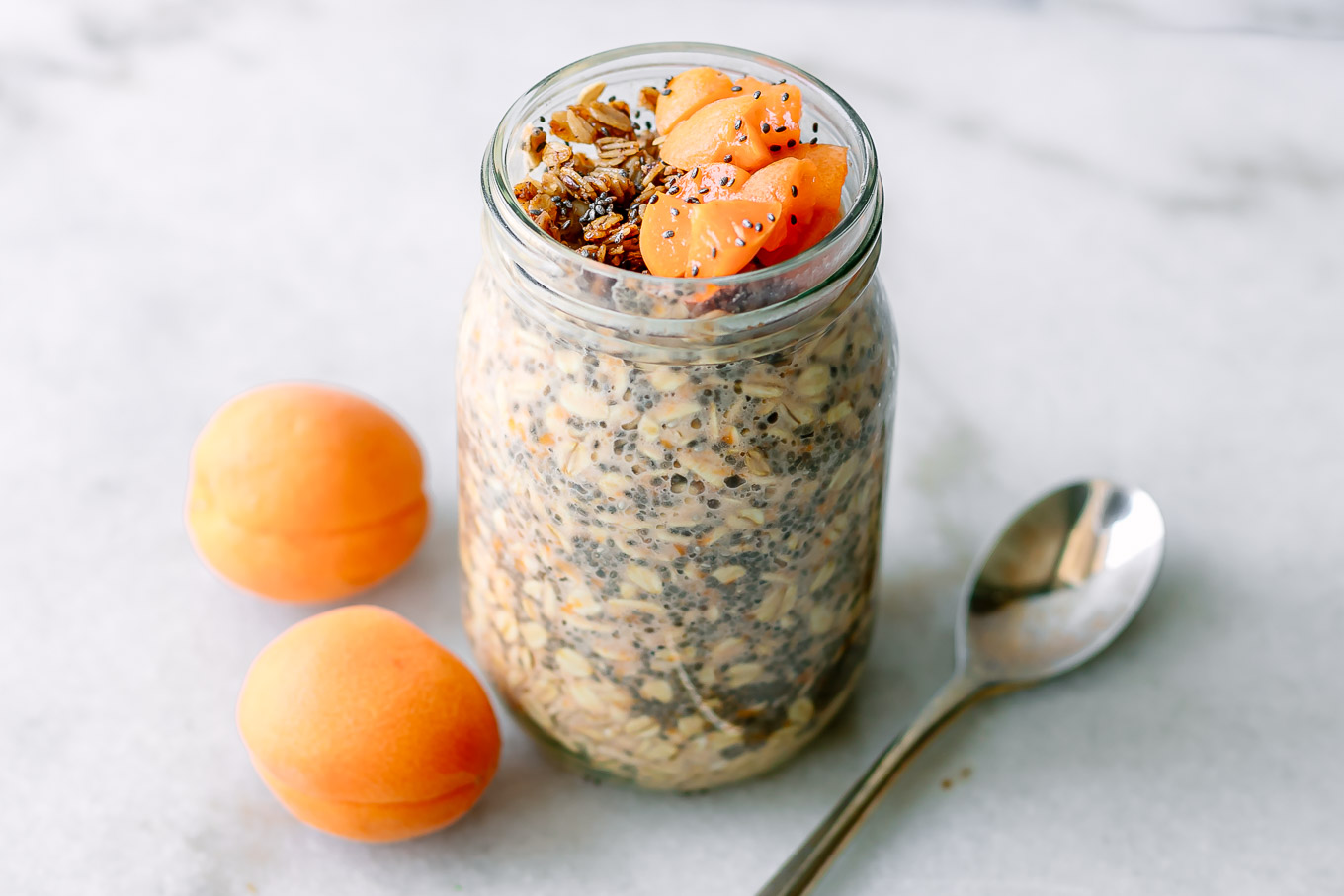 apricot flavored overnight oats garnished with granola and cut apricots on a white table
