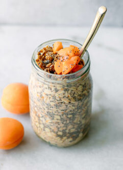 a jar of apricot overnight oats with a gold fork on a white table