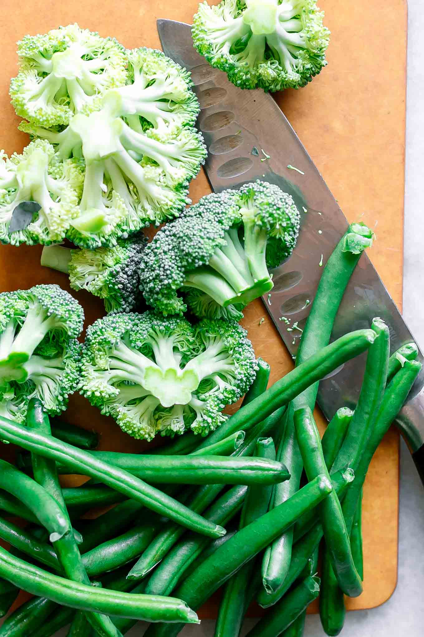 cut broccoli and green beans on a cutting board with a knife