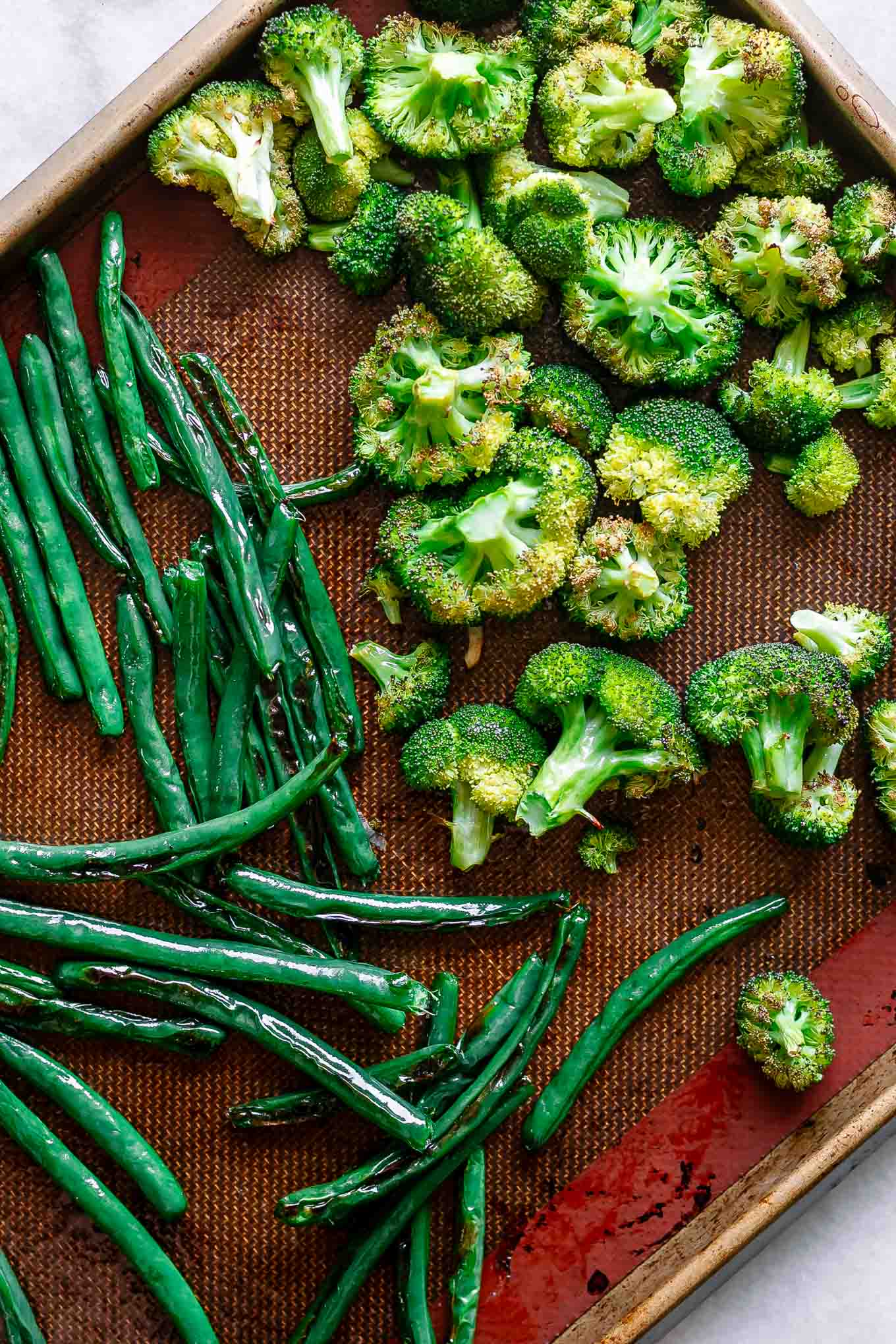 baked broccoli and greens beans on baking sheet after roasting