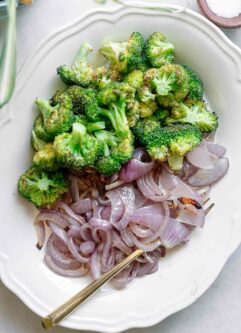 oven baked broccoli and onion on a white plate with a gold fork