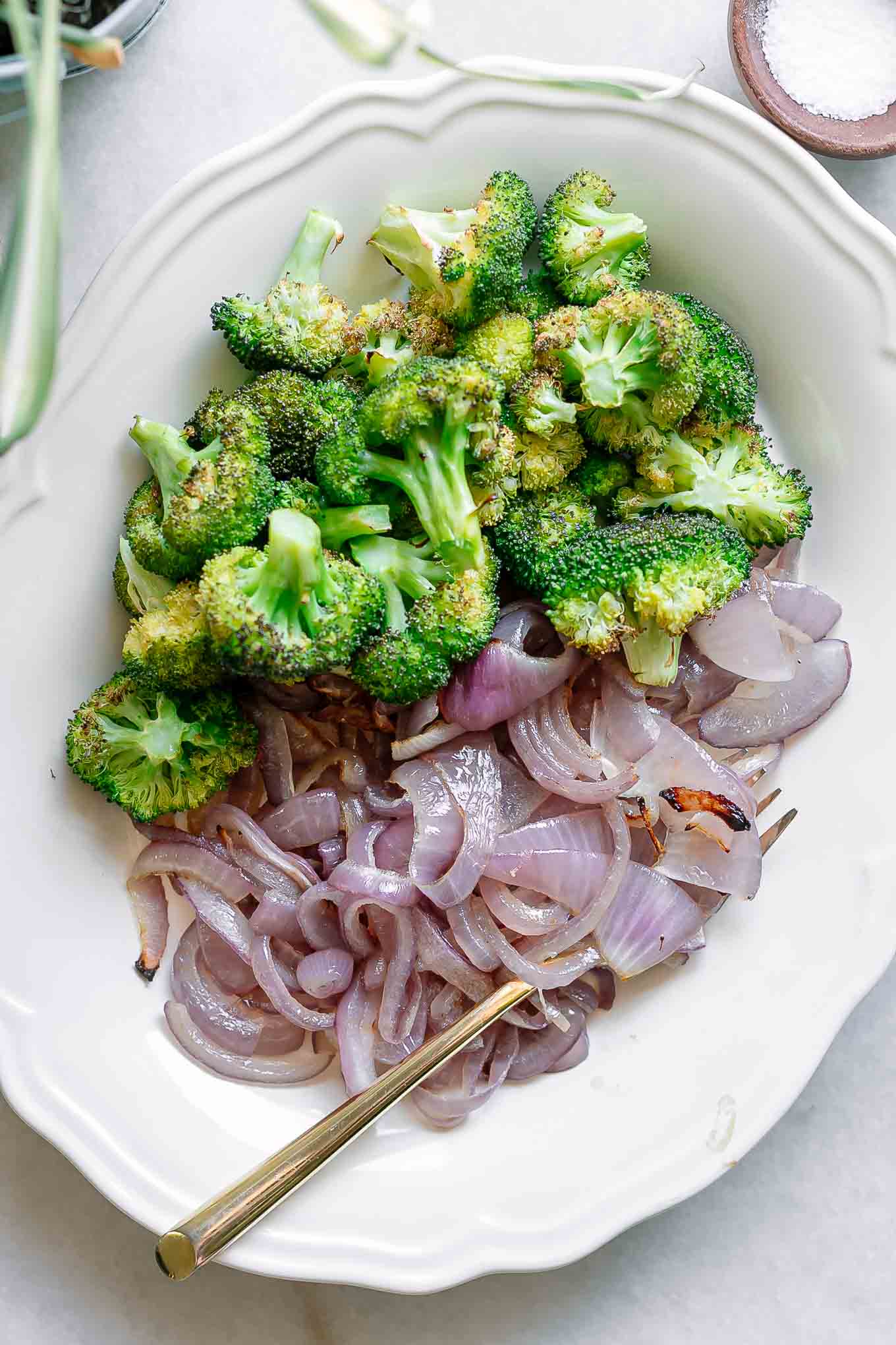 oven baked broccoli and onion on a white plate with a gold fork