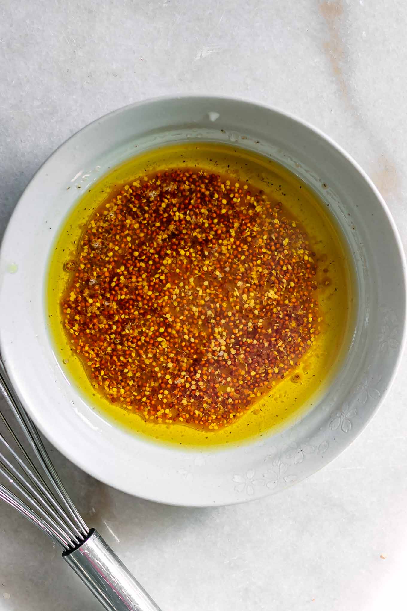 a bowl with whisked salad dressing on a white table