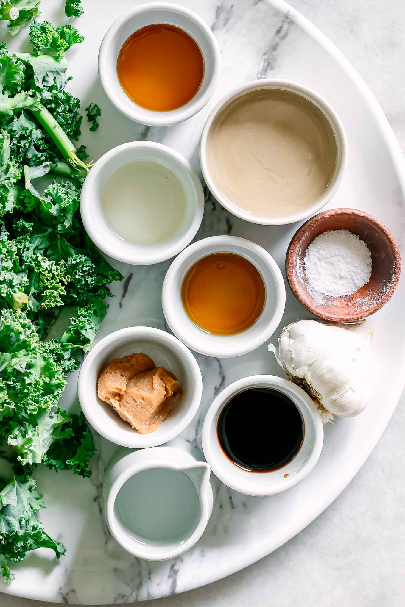 bowls of miso paste, tahini, sesame oil, maple syrup, rice vinegar, and other ingredients for a tahini and miso dressing