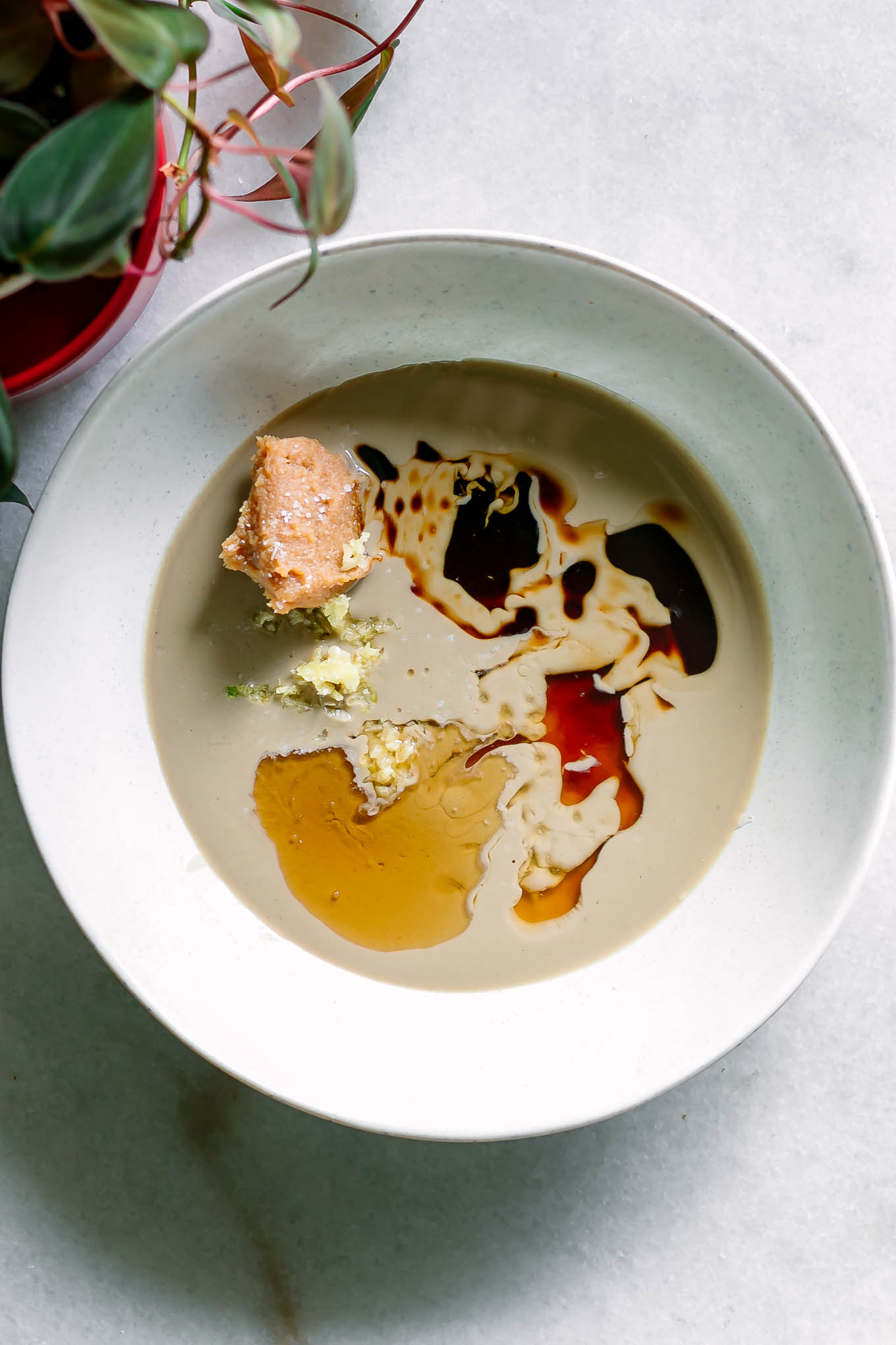 a white bowl with tahini, white miso paste, sesame oil, and other ingredients for salad dressing