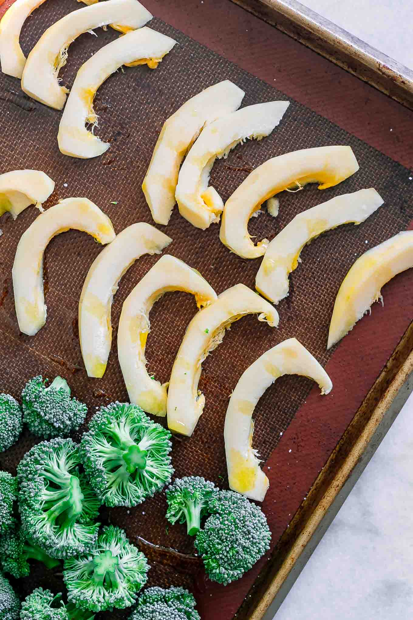 cut acorn squash and broccoli on a baking sheet before roasting