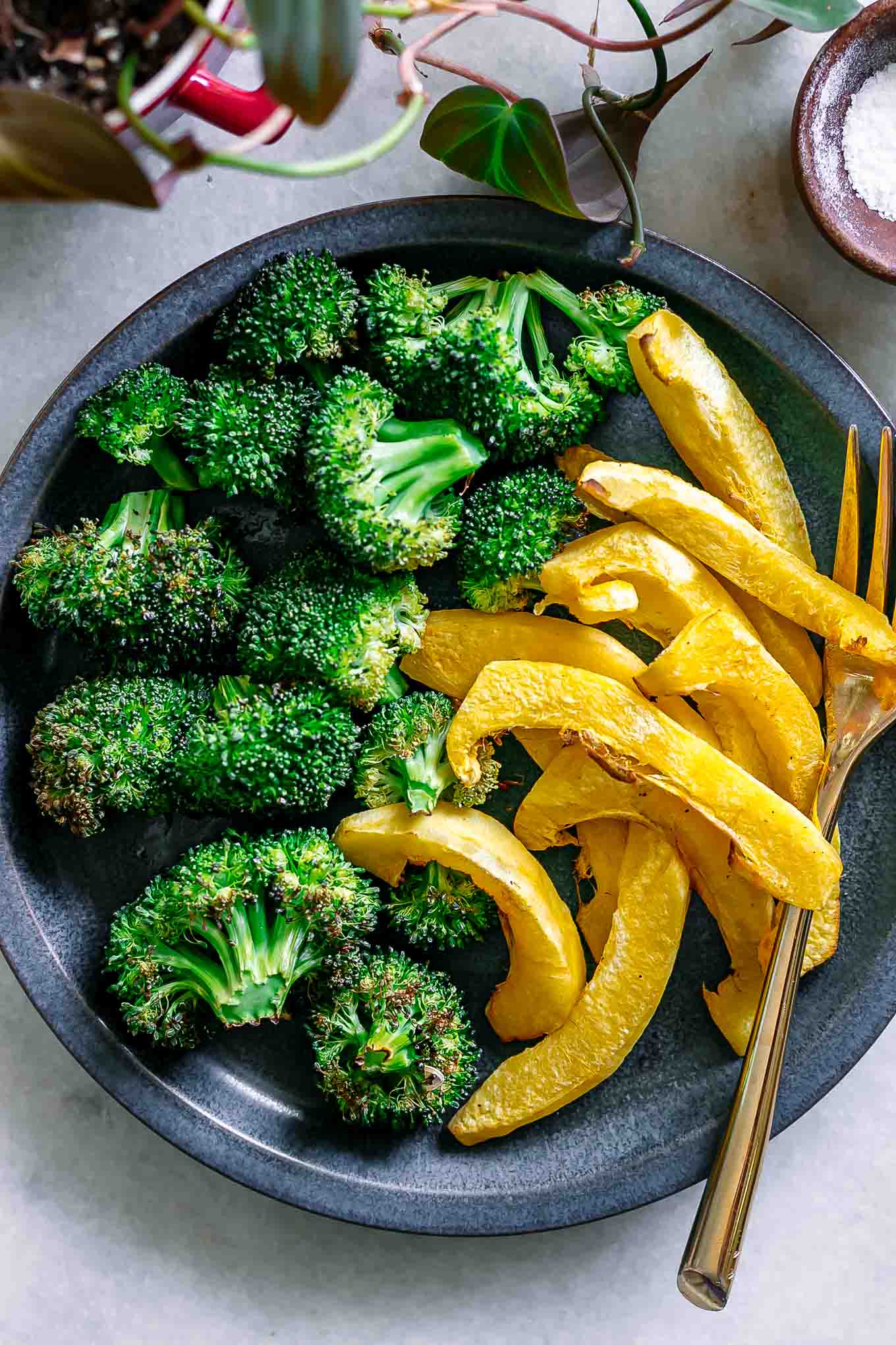 roasted acorn squash and broccoli on a blue side dish with a gold fork