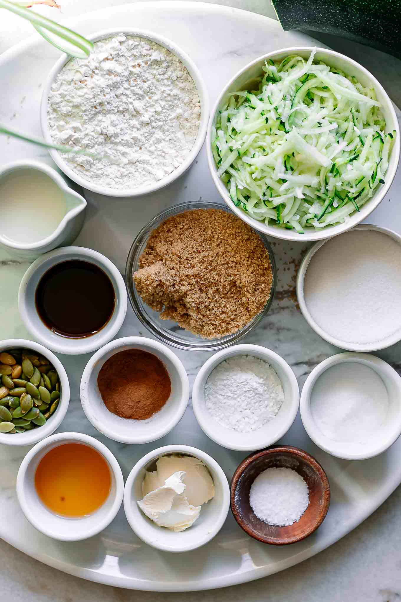bowls of flour, sugar, shredded zucchini, and other ingredients for plant-based zucchini muffins