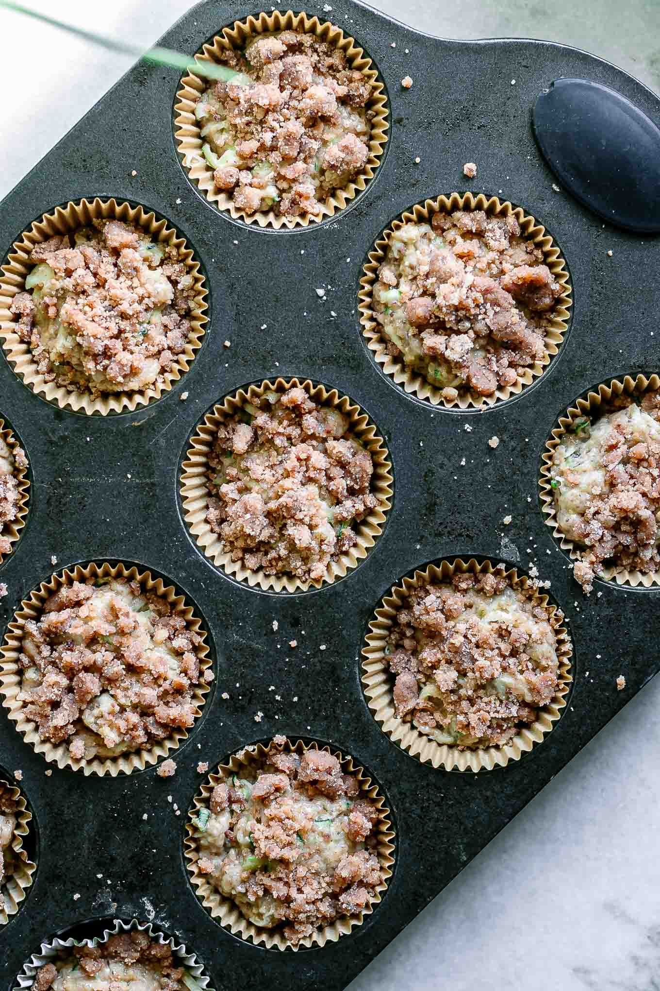 a muffin tin with zucchini muffin batter before baking