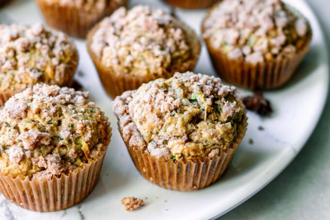 vegan zucchini muffins with a crumb topping on a white table
