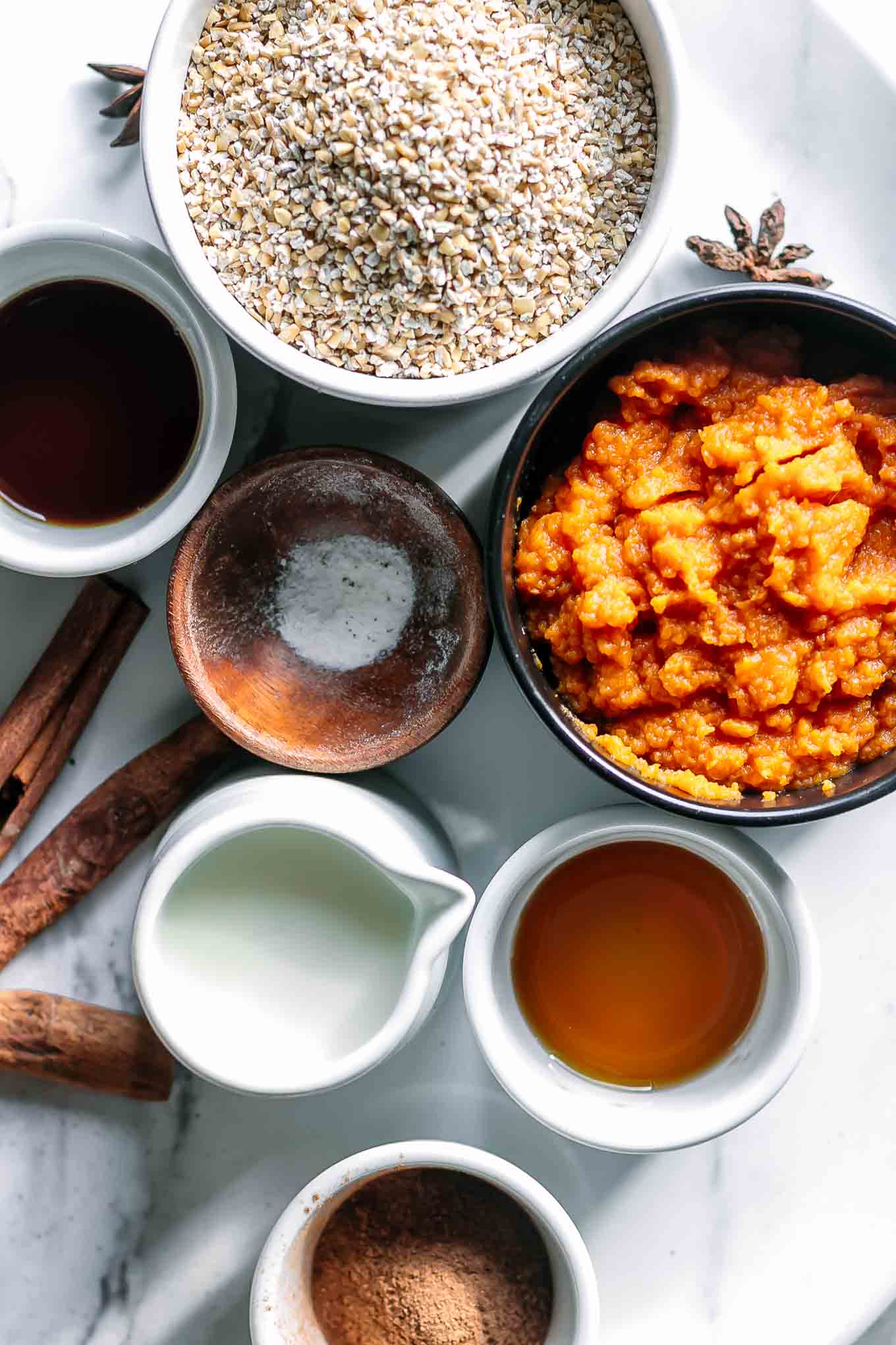 bowls of steel cut oats, pumpkin puree, maple syrup, vanilla extract, and other ingredients for pumpkin oatmeal