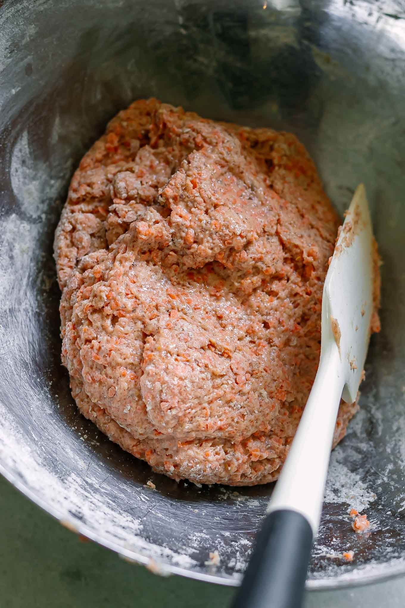 carrot cake muffin batter in a metal bowl with a white spatula