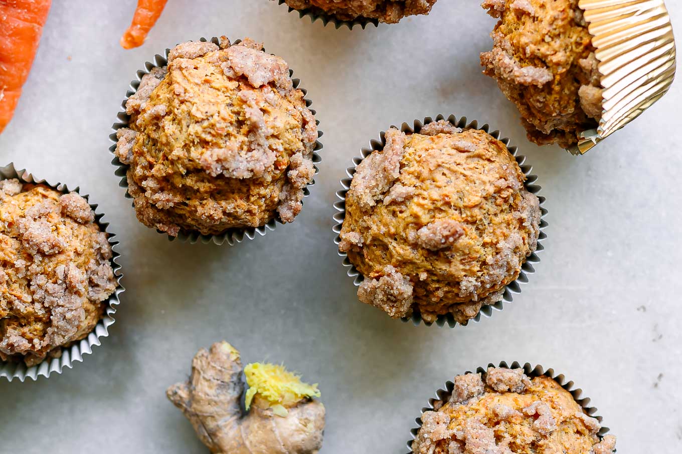 carrot cake muffins with a ginger brown sugar crumble on top on a white table