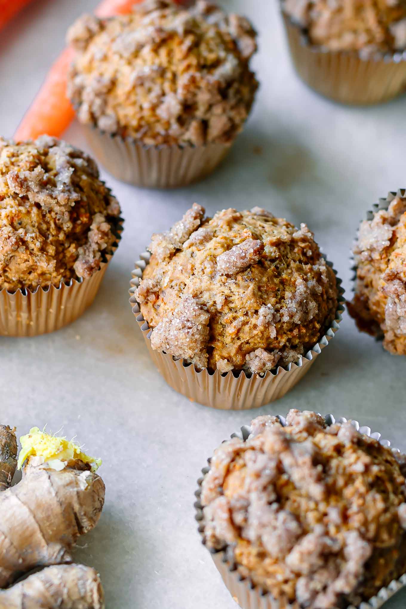 carrot cake muffins with a ginger crumble on a white table