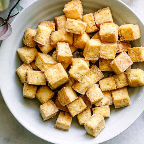 a bowl with crispy baked tofu on a white table