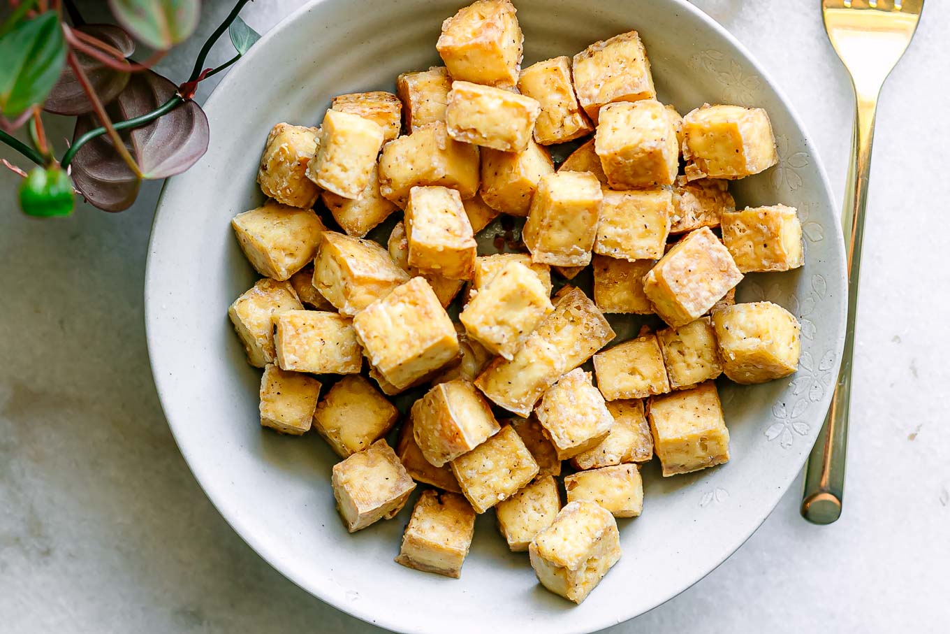 a bowl with crispy baked tofu on a white table