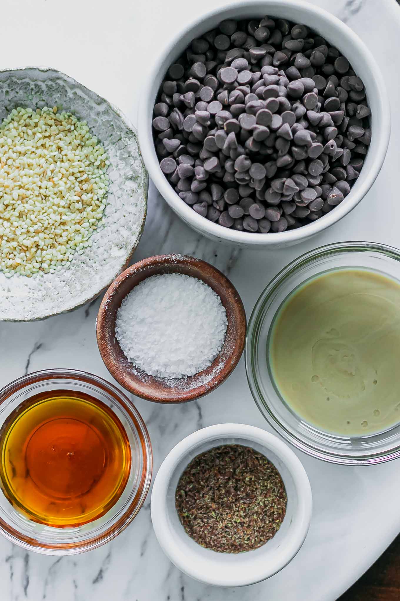 bowls of dark chocolate chips, tahini, maple syrup, salt, and sesame seeds for chocolate tahini cups