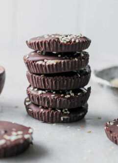 a stack of dark chocolate cups with tahini on a white table