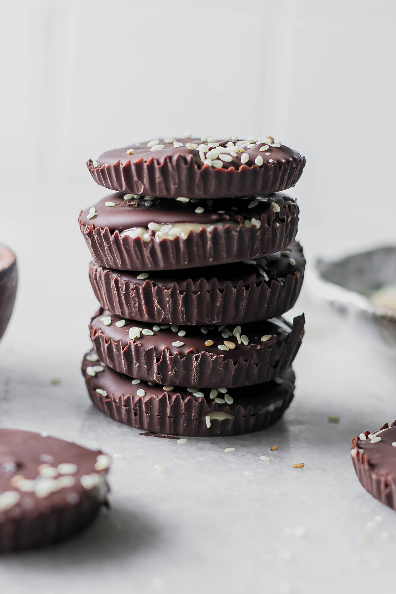 a stack of dark chocolate cups with tahini on a white table