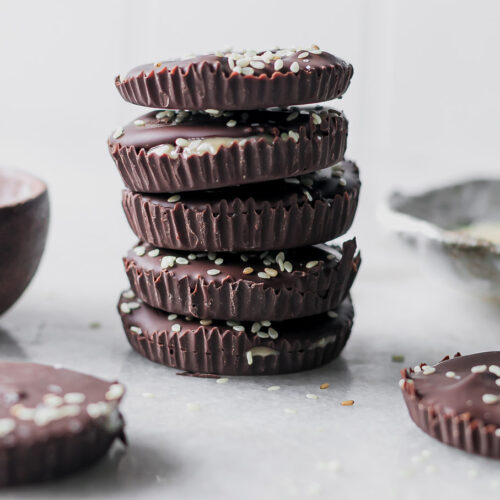 a stack of dark chocolate tahini cups on a white table