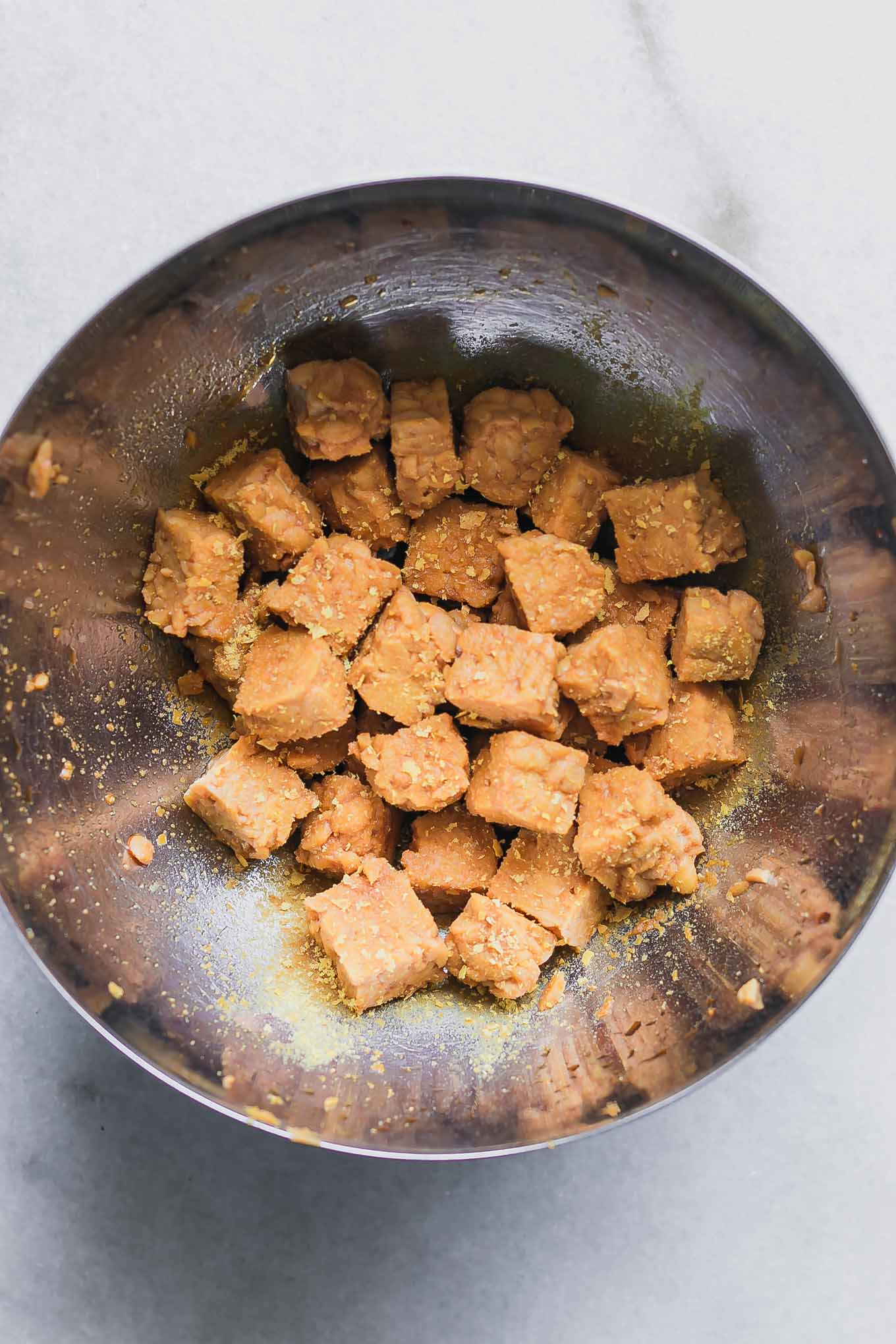 a bowl of tofu marinating in soy sauce on a white table