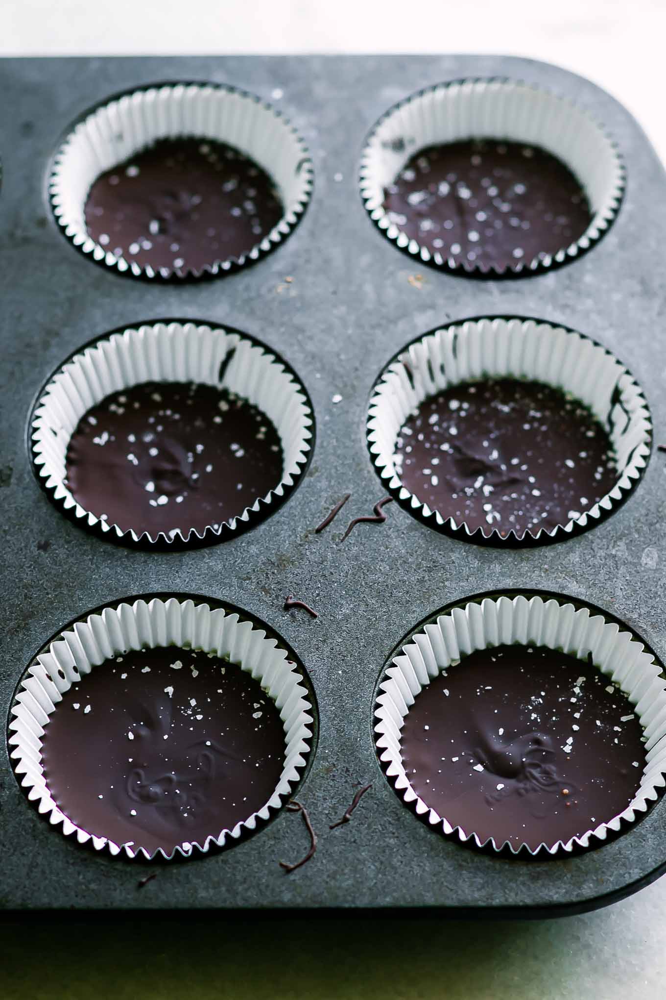 chocolate peanut butter cups in muffin liners in a muffin tin after freezing